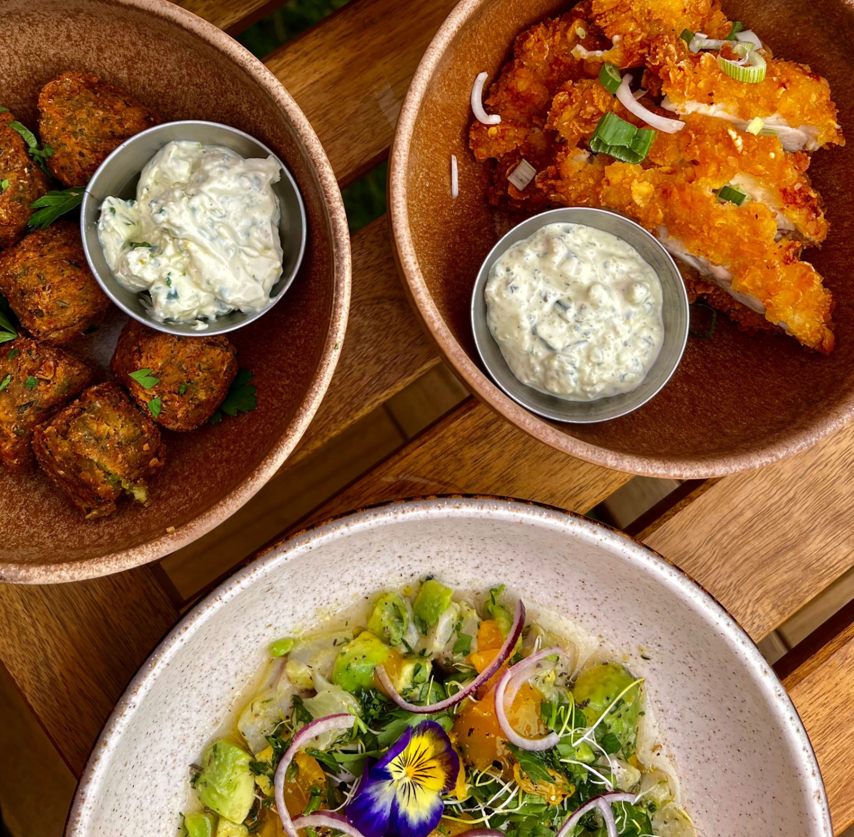Assiettes de cuisine locale et créative servies à la Guinguette du Peyrat : falafels, fish & chips et salade fraîche. - réalisé par Agence Kulte