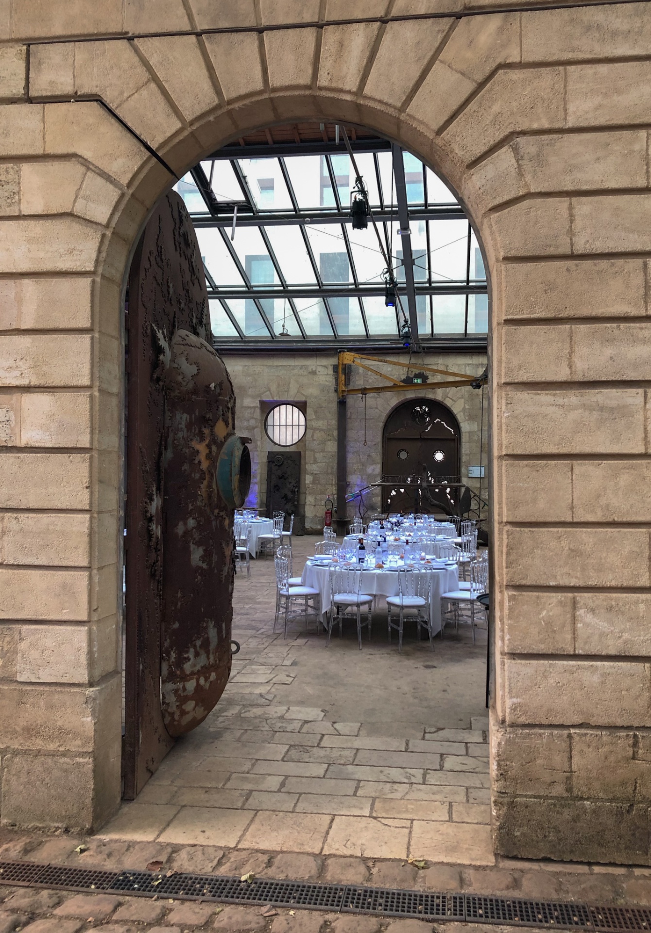 Perspective à travers une arche en pierre révélant la mise en place du dîner de gala pour le projet LESAM. - réalisé par Agence Kulte